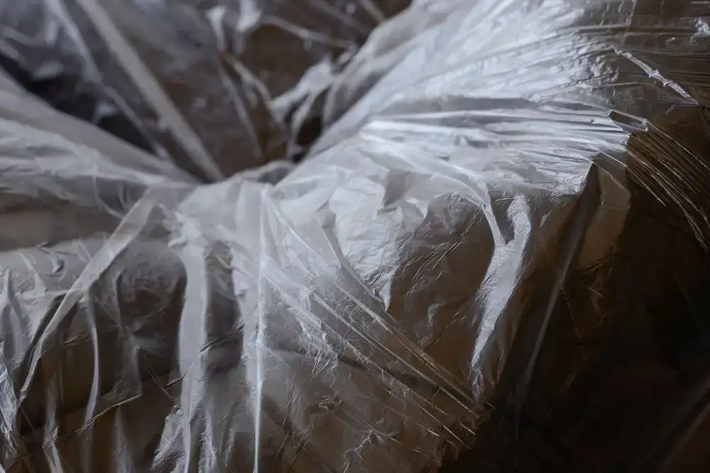 Moving team carefully placing wrapped furniture into a large wooden storage crate