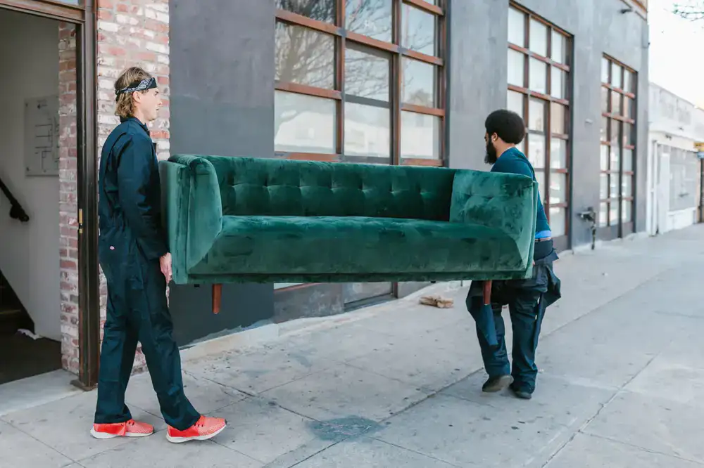 Moving team carefully wrapping and transporting large furniture
